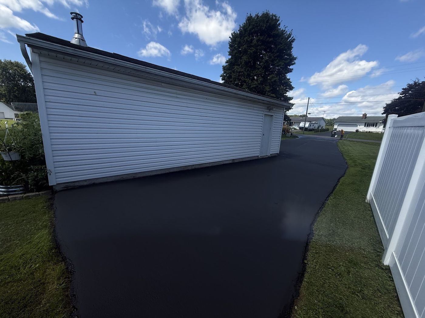 Fresh asphalt driveway beside a white garage